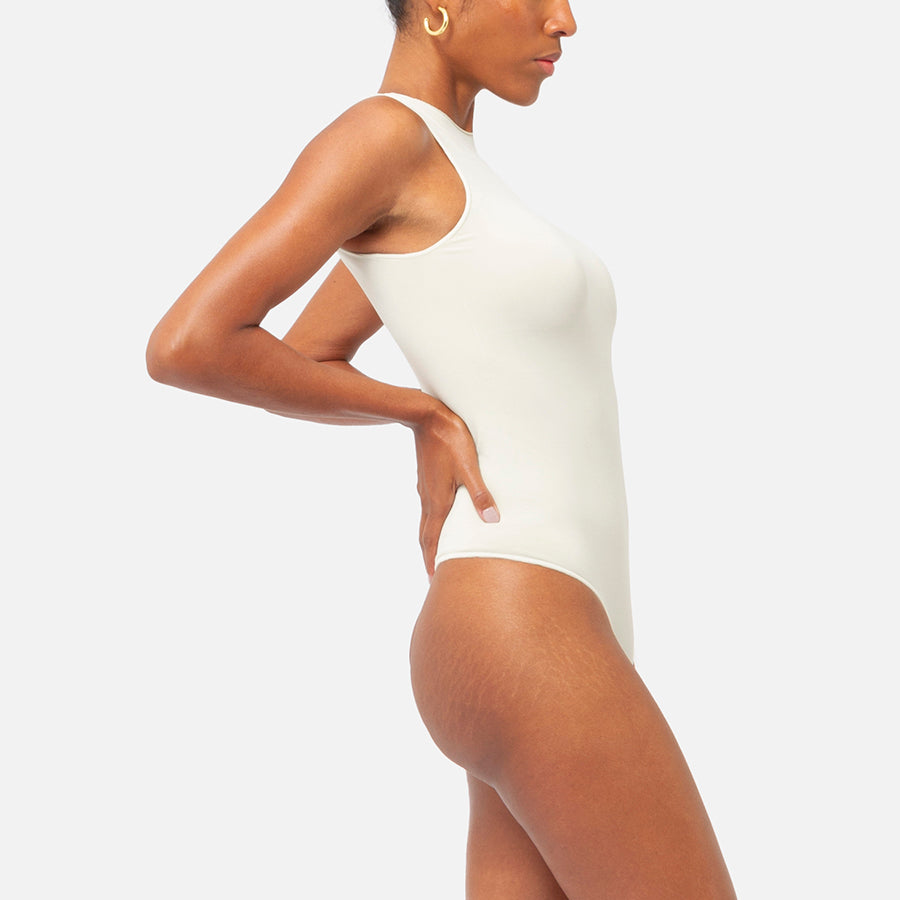 modelo posando de lado nuestro bodysuit sin manga color Bone